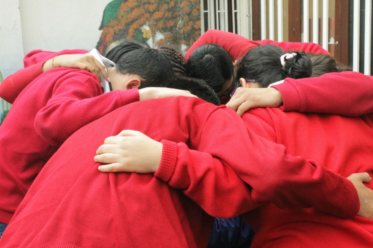 Foto de niños de la fundacion frine haciendo un circulo abrazados